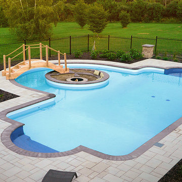 Pool with a firepit by Exact Landscapes