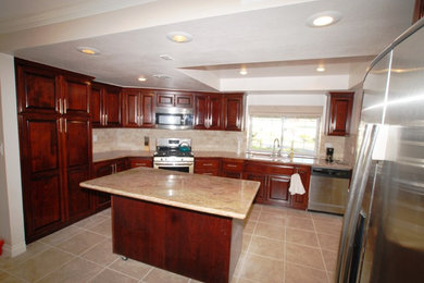 Open concept kitchen - large traditional u-shaped porcelain tile open concept kitchen idea in Orange County with a double-bowl sink, raised-panel cabinets, dark wood cabinets, granite countertops, beige backsplash, subway tile backsplash, stainless steel appliances and an island
