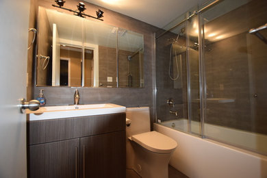 Inspiration for a mid-sized contemporary master ceramic tile and brown tile tub/shower combo remodel in Calgary with flat-panel cabinets, a one-piece toilet, a vessel sink, a hinged shower door and dark wood cabinets