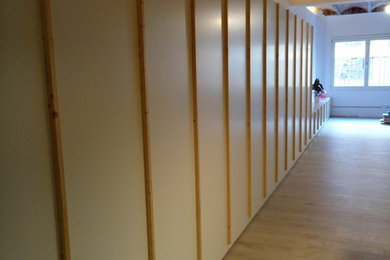 Imagen de armario unisex moderno con armarios con paneles lisos, puertas de armario de madera clara, suelo de madera clara y suelo beige