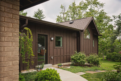 Inspiration for a mid-sized 1960s brown one-story concrete fiberboard and board and batten exterior home remodel in St Louis with a shingle roof and a brown roof