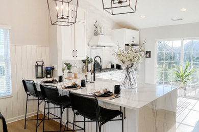 Inspiration for a large country l-shaped light wood floor and vaulted ceiling open concept kitchen remodel in Atlanta with shaker cabinets, white cabinets, marble countertops, white backsplash, stainless steel appliances, a peninsula, yellow countertops and a farmhouse sink