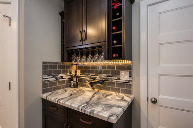 Small trendy single-wall porcelain tile home bar photo in Calgary with shaker cabinets, dark wood cabinets, marble countertops, gray backsplash and subway tile backsplash