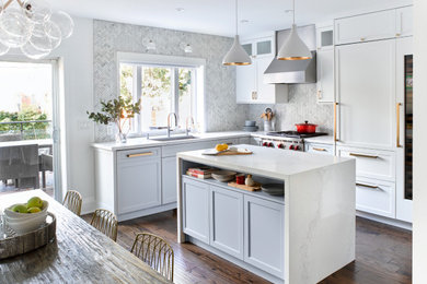 Mid-sized transitional l-shaped eat-in kitchen in Toronto with a single-bowl sink, shaker cabinets, white cabinets, quartz benchtops, grey splashback, mosaic tile splashback, panelled appliances, medium hardwood floors, with island, brown floor and white benchtop.