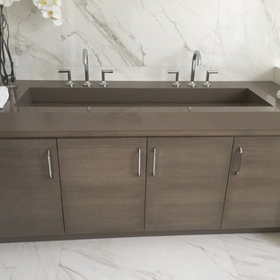 Trendy gray tile and marble tile marble floor and gray floor bathroom photo in Miami with flat-panel cabinets, dark wood cabinets, a trough sink and quartz countertops
