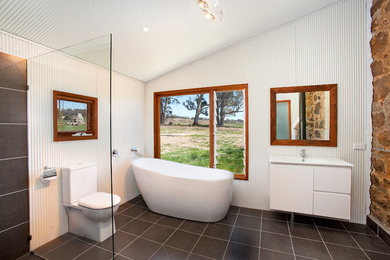 Industrial bathroom in Sydney with a freestanding tub, an open shower and an open shower.