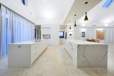 Design ideas for a mid-sized modern galley eat-in kitchen in Canberra - Queanbeyan with an undermount sink, flat-panel cabinets, white cabinets, marble benchtops, white floor, white benchtop, ceramic floors and multiple islands.