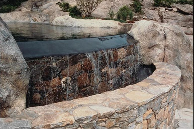 Large island style backyard stone and custom-shaped natural pool photo in Other