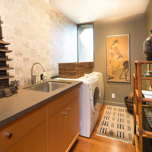 Immagine di una sala lavanderia etnica con lavello sottopiano, ante lisce, ante in legno scuro, pareti grigie, pavimento in legno massello medio e lavatrice e asciugatrice affiancate