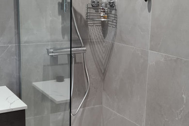 Photo of a medium sized modern grey and white ensuite bathroom in Other with flat-panel cabinets, dark wood cabinets, a walk-in shower, a wall mounted toilet, grey tiles, porcelain tiles, grey walls, ceramic flooring, a vessel sink, quartz worktops, grey floors, an open shower, white worktops, feature lighting, a single sink and a floating vanity unit.