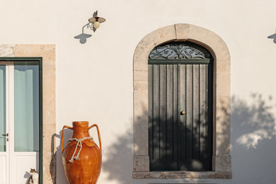 Idee per un ampio ingresso mediterraneo con pareti bianche, pavimento in cemento, una porta a due ante, una porta verde e pavimento marrone