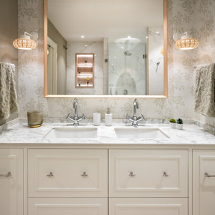Photo of a mid-sized transitional master bathroom in Other with raised-panel cabinets, white cabinets, a curbless shower, white tile, green walls, laminate floors, an undermount sink, granite benchtops, brown floor, white benchtops, a double vanity, a built-in vanity and wallpaper.