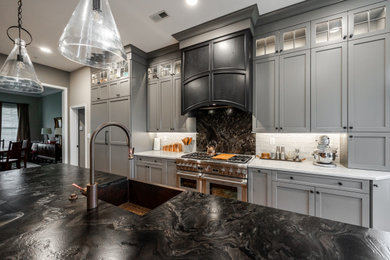 Inspiration for a large industrial galley brick floor eat-in kitchen remodel in Philadelphia with a farmhouse sink, shaker cabinets, gray cabinets, granite countertops, granite backsplash, paneled appliances, an island and black countertops