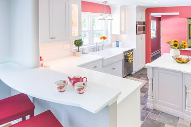Example of a mid-sized transitional u-shaped porcelain tile and gray floor eat-in kitchen design in Philadelphia with a farmhouse sink, recessed-panel cabinets, white cabinets, quartz countertops, white backsplash, glass tile backsplash, stainless steel appliances, an island and white countertops