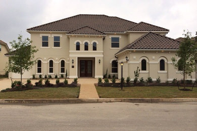 Large mediterranean beige two-story stucco house exterior idea with a hip roof and a tile roof