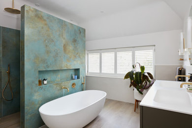 Inspiration for a large contemporary ensuite bathroom in London with a freestanding bath, green tiles, an integrated sink, a hinged door, double sinks, a floating vanity unit, grey cabinets, white walls, wood-effect flooring, engineered stone worktops, beige floors and white worktops.