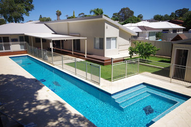 Design ideas for a large modern backyard l-shaped lap pool in Perth with a pool house and natural stone pavers.
