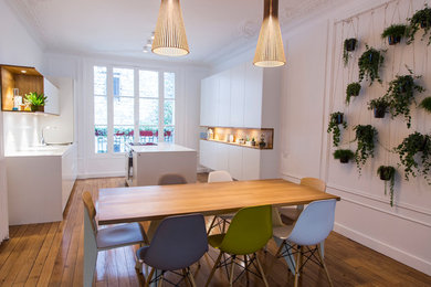 Scandinavian kitchen/dining combo in Paris with white walls, medium hardwood floors and brown floor.