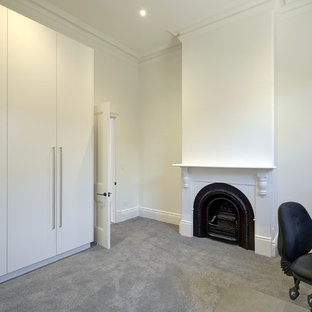 Photo of a medium sized modern study in Adelaide with white walls, carpet, a standard fireplace, a wooden fireplace surround, a freestanding desk and grey floors.