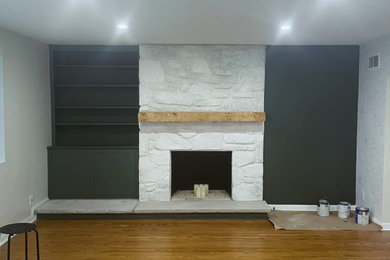 Modelo de salón actual sin televisor con paredes negras, suelo de madera en tonos medios, todas las chimeneas y marco de chimenea de piedra