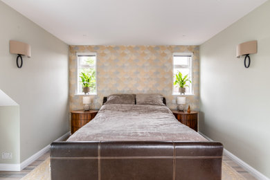 Ejemplo de dormitorio principal contemporáneo de tamaño medio con paredes verdes, suelo laminado, suelo gris y papel pintado