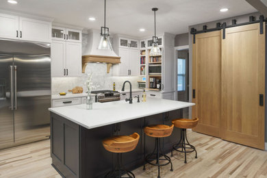 Inspiration for a large country u-shaped light wood floor and beige floor eat-in kitchen remodel in Columbus with a farmhouse sink, recessed-panel cabinets, white cabinets, quartz countertops, white backsplash, stone tile backsplash, stainless steel appliances, an island and white countertops