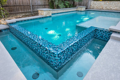 Example of a mid-sized minimalist backyard rectangular infinity pool design in Austin with decking