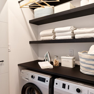 Inspiration for a small contemporary single-wall concrete floor and gray floor laundry closet remodel in Vancouver with open cabinets, black cabinets, wood countertops, white walls, a side-by-side washer/dryer and black countertops