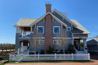 Ejemplo de fachada de casa gris y gris tradicional con revestimiento de madera, tejado a dos aguas, tejado de teja de madera y teja