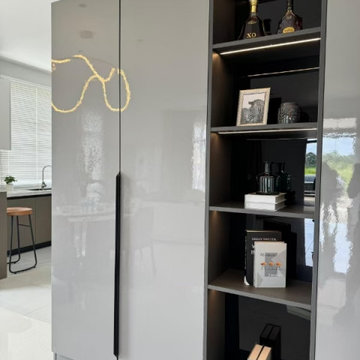 Angled View of Illuminated Display Cabinet with Kitchen Reflected on Gloss Panel