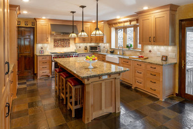 Large arts and crafts u-shaped multicolored floor kitchen photo in Other with a farmhouse sink, beaded inset cabinets, light wood cabinets, granite countertops, beige backsplash, brick backsplash, paneled appliances, an island and multicolored countertops