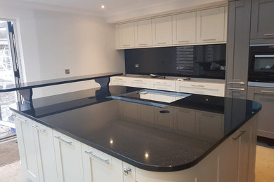 Inspiration for a large contemporary open plan kitchen in Other with recessed-panel cabinets, white cabinets, granite worktops, black splashback, stone slab splashback, an island and black worktops.