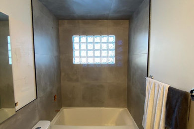 Modelo de cuarto de baño industrial de tamaño medio con bañera empotrada, combinación de ducha y bañera, baldosas y/o azulejos grises, baldosas y/o azulejos de porcelana, suelo de baldosas de porcelana, suelo gris y ducha con cortina