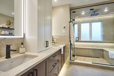 Example of a large transitional master beige tile and porcelain tile beige floor, double-sink and porcelain tile bathroom design in Ottawa with brown cabinets, an undermount sink, a hinged shower door, beige countertops, shaker cabinets, a one-piece toilet, beige walls, quartz countertops and a built-in vanity