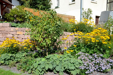 Mittelgroßer Landhaus Garten im Sommer, neben dem Haus mit Blumenbeet, direkter Sonneneinstrahlung und Natursteinplatten in Frankfurt am Main