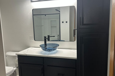 Example of a mid-sized minimalist master white tile and porcelain tile ceramic tile, gray floor and single-sink alcove shower design in Other with raised-panel cabinets, black cabinets, a two-piece toilet, white walls, a vessel sink, quartzite countertops, a hinged shower door, white countertops, a niche and a built-in vanity