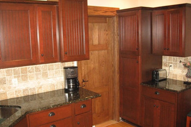Photo of a mid-sized arts and crafts galley kitchen pantry in Grand Rapids with beaded inset cabinets, dark wood cabinets, granite benchtops, beige splashback, stone tile splashback, an undermount sink and stainless steel appliances.