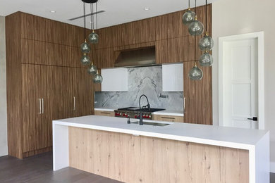 Photo of a large contemporary l-shaped open plan kitchen in Miami with an undermount sink, flat-panel cabinets, quartz benchtops, grey splashback, marble splashback, stainless steel appliances, porcelain floors, with island, brown floor and white benchtop.