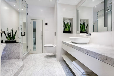 Example of a trendy porcelain tile and white floor freestanding bathtub design in Vancouver with a wall-mount toilet, white walls, a vessel sink, marble countertops and a hinged shower door