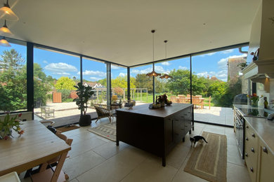Inspiration for a medium sized contemporary galley open plan kitchen with a breakfast bar, a belfast sink, beaded cabinets, green cabinets, marble worktops, white splashback, marble splashback, integrated appliances, travertine flooring, beige floors and white worktops.