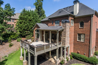 Example of a large transitional backyard deck design in Atlanta with a roof extension