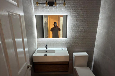 Powder room - modern gray tile and stone tile concrete floor powder room idea in Boston with raised-panel cabinets, brown cabinets, a one-piece toilet, quartz countertops and a floating vanity