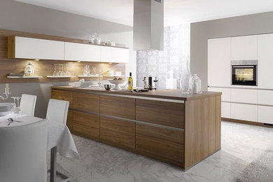 Photo of a mid-sized modern galley eat-in kitchen in New York with flat-panel cabinets, white cabinets, glass benchtops and with island.