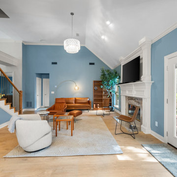 Open concept living room with vaulted ceiling and white fireplace mantle