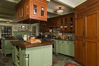 Kitchen - large traditional single-wall slate floor kitchen idea in New York with a farmhouse sink, beaded inset cabinets, green cabinets, soapstone countertops, gray backsplash, stone slab backsplash, paneled appliances and an island