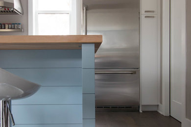 Inspiration for a large contemporary l-shaped medium tone wood floor eat-in kitchen remodel in Detroit with an undermount sink, flat-panel cabinets, white cabinets, quartz countertops, stainless steel appliances and an island