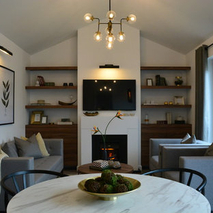 Foto di un piccolo soggiorno minimalista stile loft con pareti bianche, pavimento in laminato, camino classico, cornice del camino in legno, TV a parete e pavimento grigio