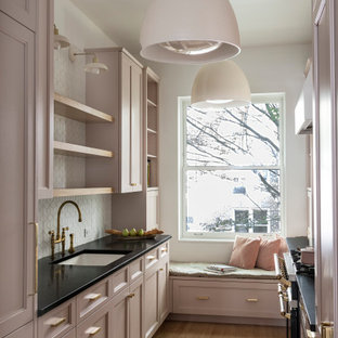 Photo of a small transitional galley separate kitchen in New York with open cabinets, pink cabinets, soapstone benchtops, white splashback, ceramic splashback and black benchtop.