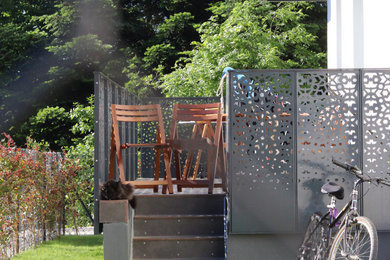 Réalisation d'une terrasse au rez-de-chaussée design avec des solutions pour vis-à-vis et un garde-corps en métal.
