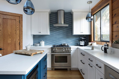 Example of a mid-sized trendy u-shaped wood ceiling, beige floor and light wood floor kitchen pantry design in San Francisco with a farmhouse sink, white cabinets, blue backsplash, stainless steel appliances, an island, white countertops, shaker cabinets, quartz countertops and ceramic backsplash